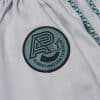 Close view of round Albino and Preto DCDT badge on gray kids gi pants